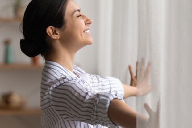 smiling and looking out of window curtains