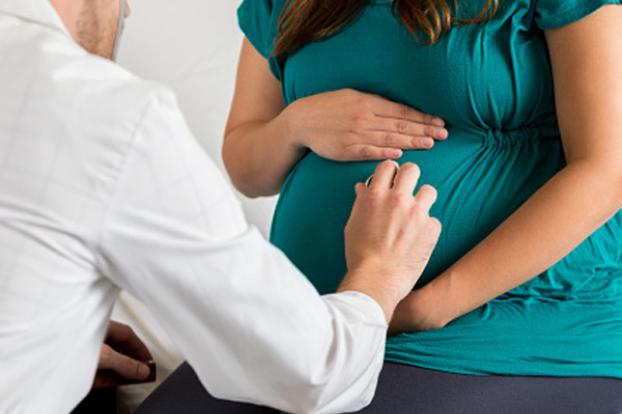 Physician checking pregnant belly.