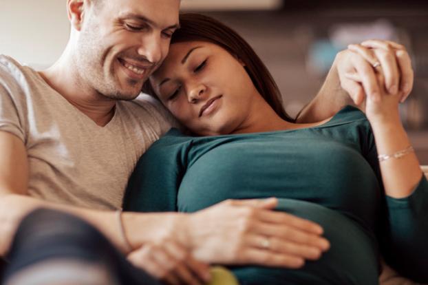 Couple with hand on pregnant belly in green shirt.