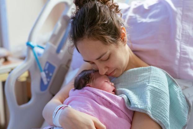 Sweet newborn in mom's arms in hospital bed.