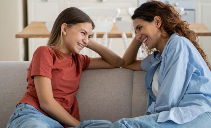 Mom and preteen daughter talk on couch