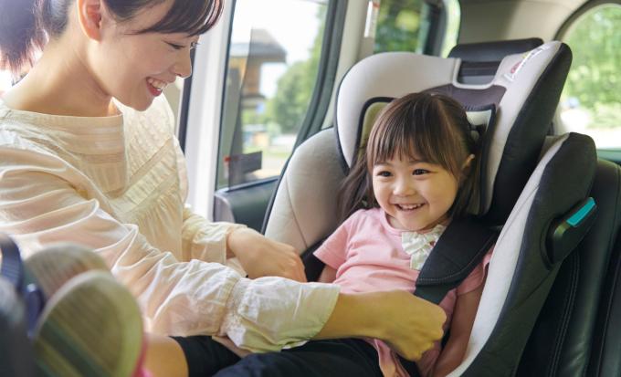 Woman straps her child into a car seat