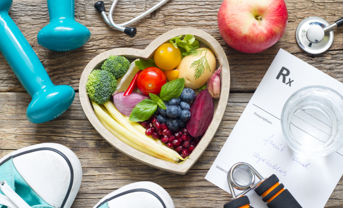 a bowl of healthy food sits next to weights and a prescription