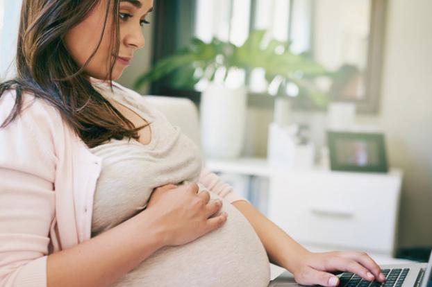 Pregnant and looking on a laptop computer.