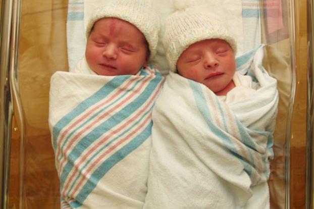 Newborn twin infants swaddled and in bassinet together.