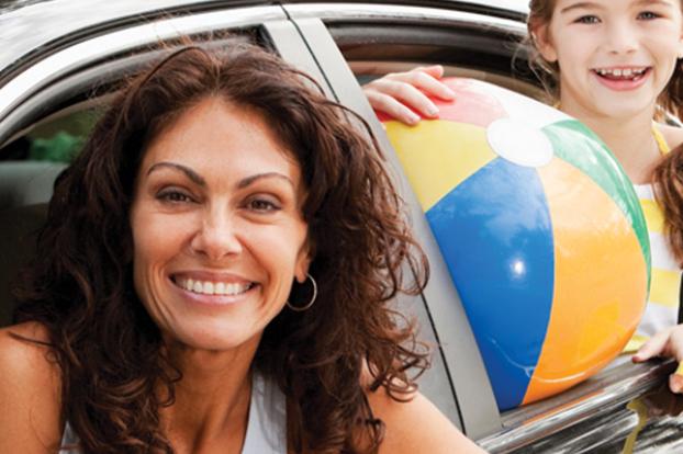 Busy mom in car with daughter and beach ball.